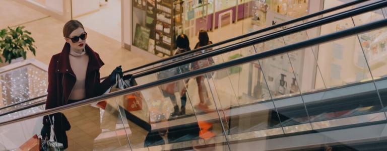 Frau mit Einkäufen auf einer Rolltreppe in einem Geschäft