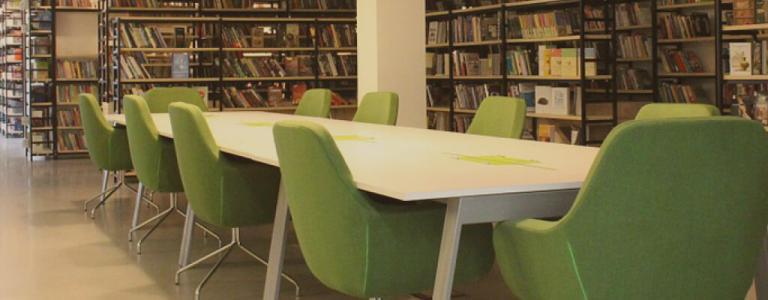 Tisch mit grünen Stühlen in einer Bibliothek